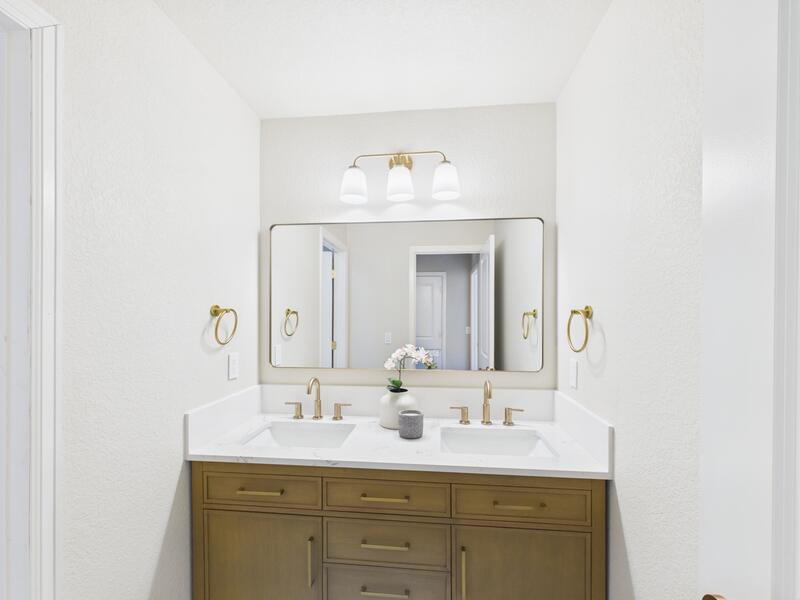 Bathroom with a double vanity, brass fixtures, and framed mirrors
