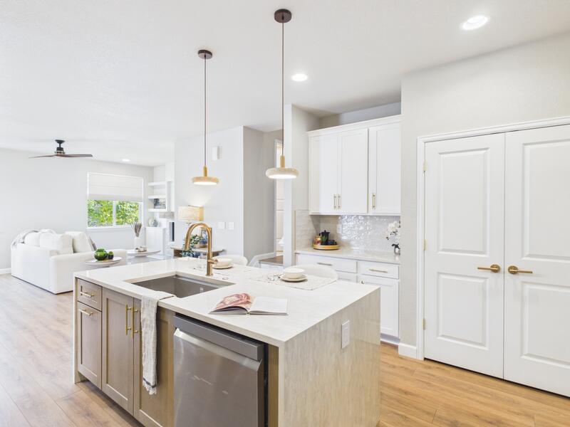 Kitchen island and pantry doors with the open great room beyond