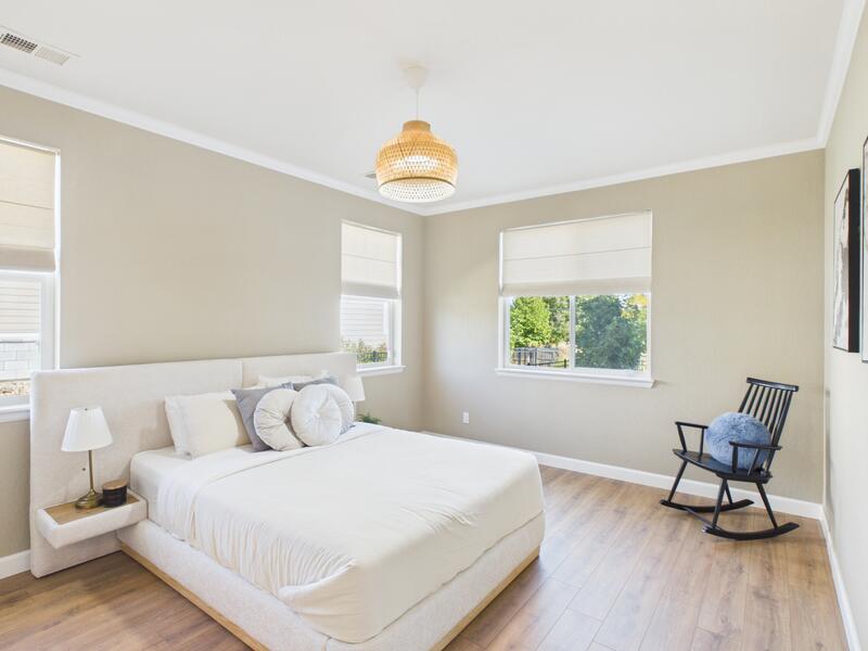 Main-level second primary suite bedroom with large windows and a rocking chair