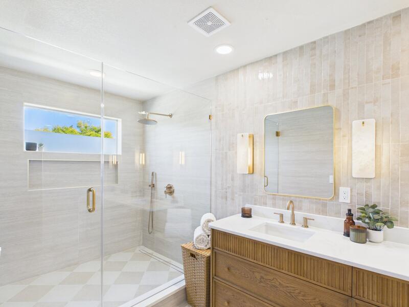 Renovated primary bathroom with an oversized walk-in shower, checkerboard floor tile, and fluted oak vanity