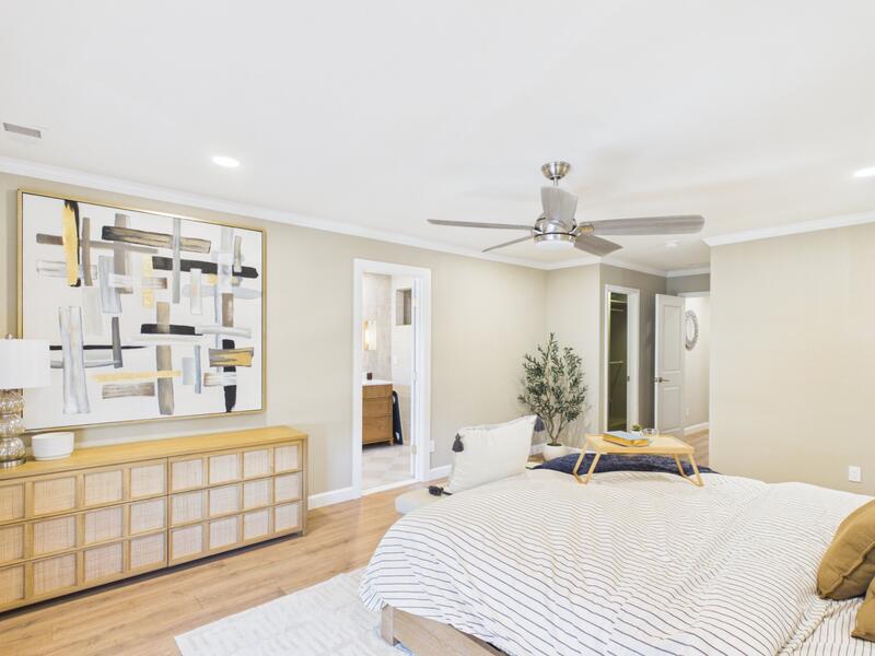 Primary bedroom with large artwork, a dresser, and doorways to the bathroom and closet